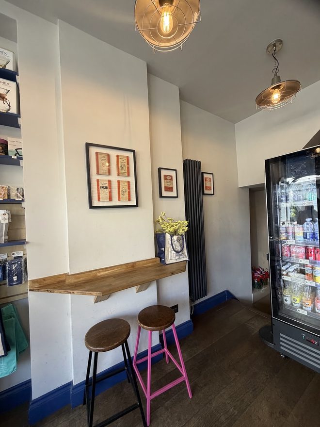 Interior of the café with the wall bench, pink stools and framed prints
